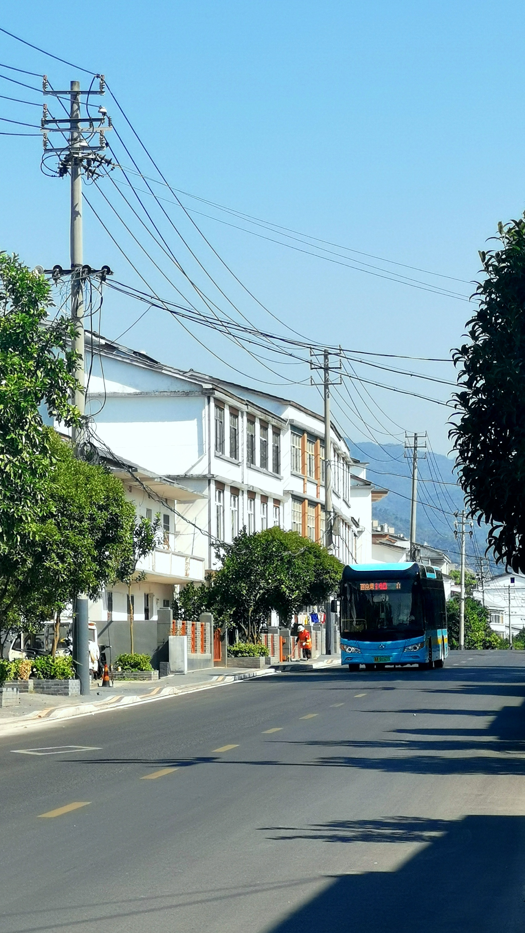 蓝色公交车行驶于乡村道路的日常景象