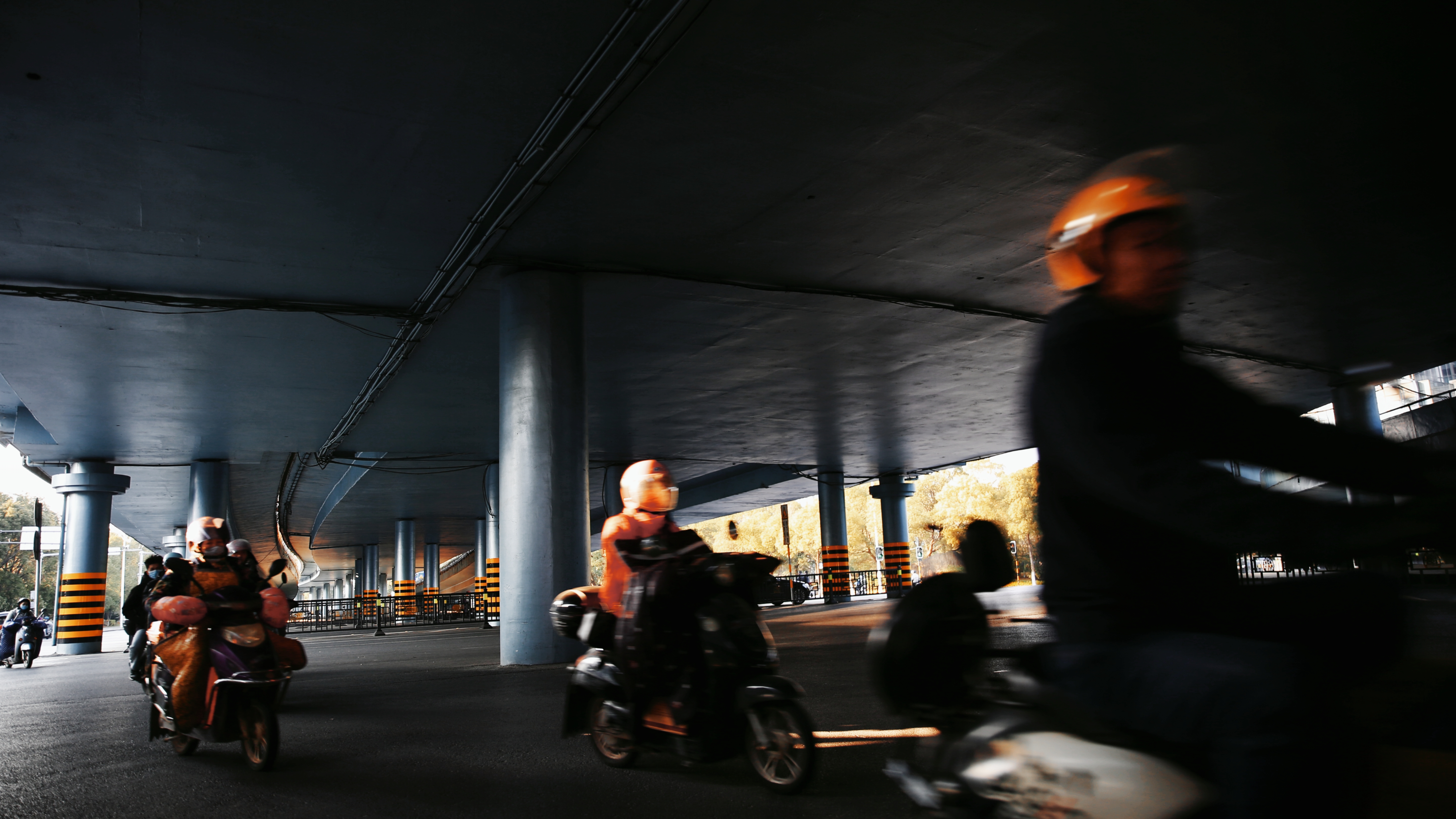 桥下道路上骑行的摩托车群像