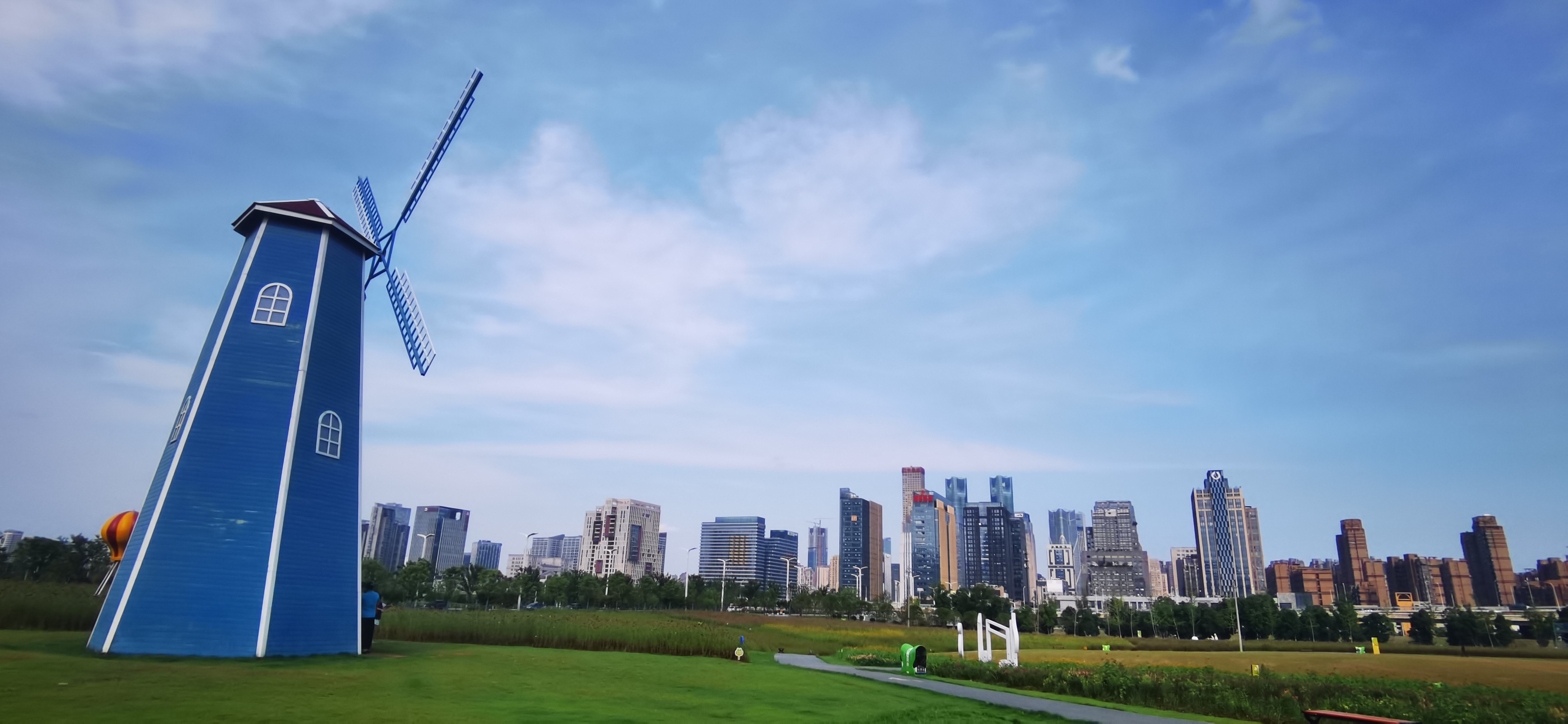 蓝色彩绘风车矗立，城市绿地风景美如画