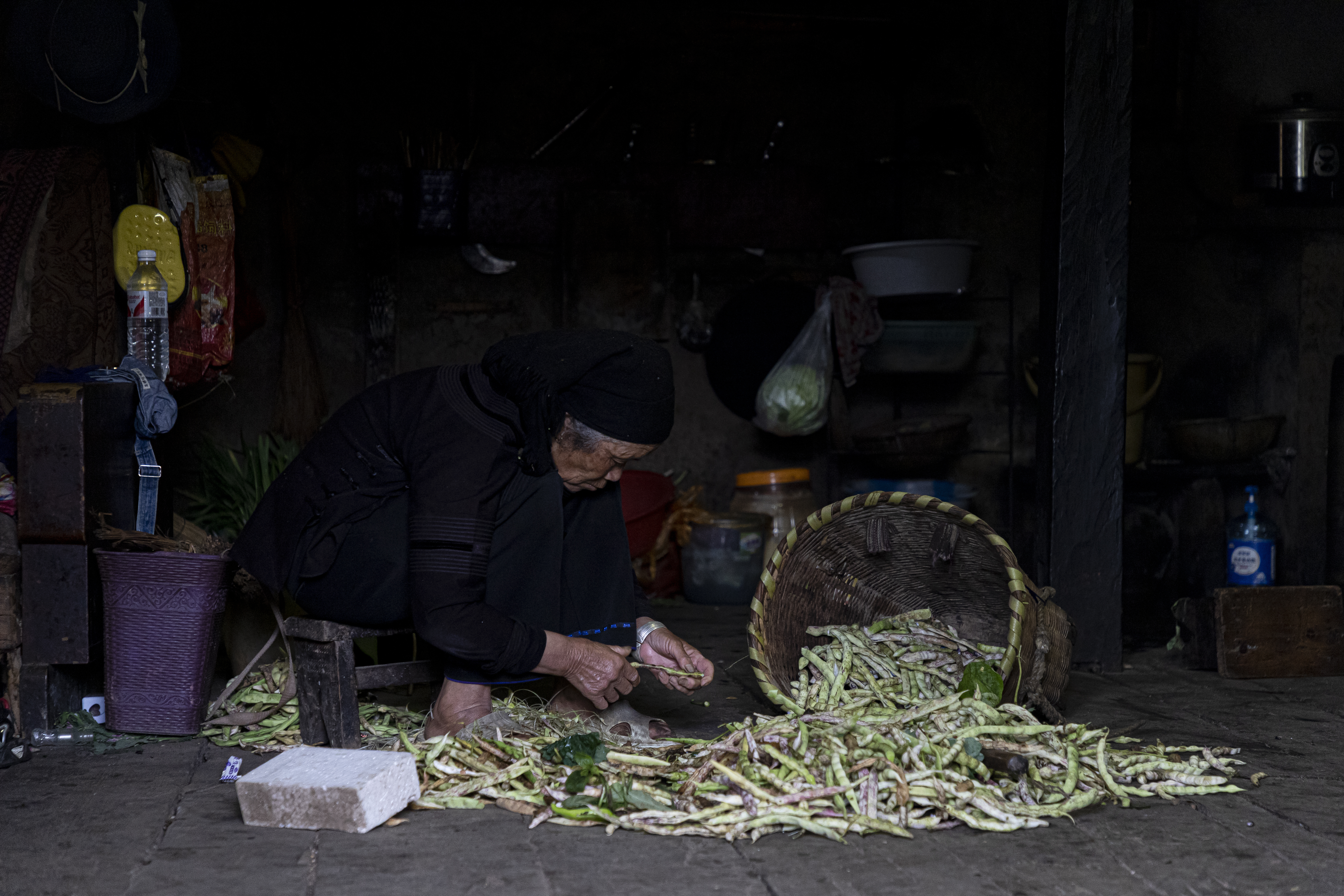 农妇在昏暗小屋中处理蔬菜的质朴生活景象