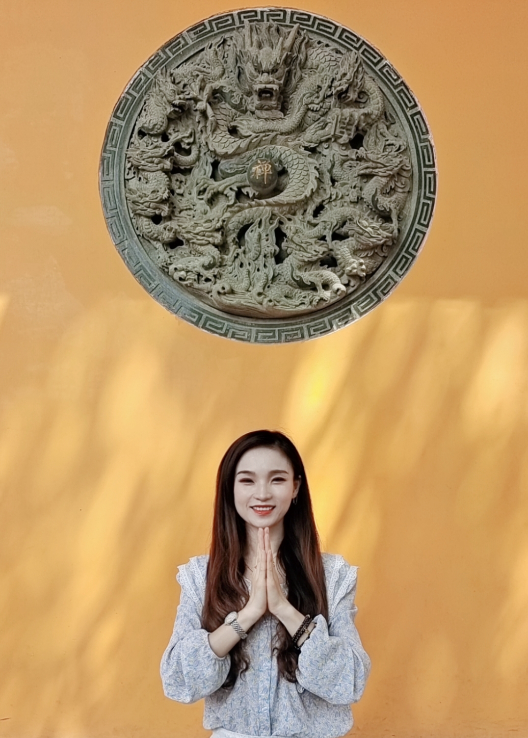 女子在精美龙雕前双手合十优雅气质