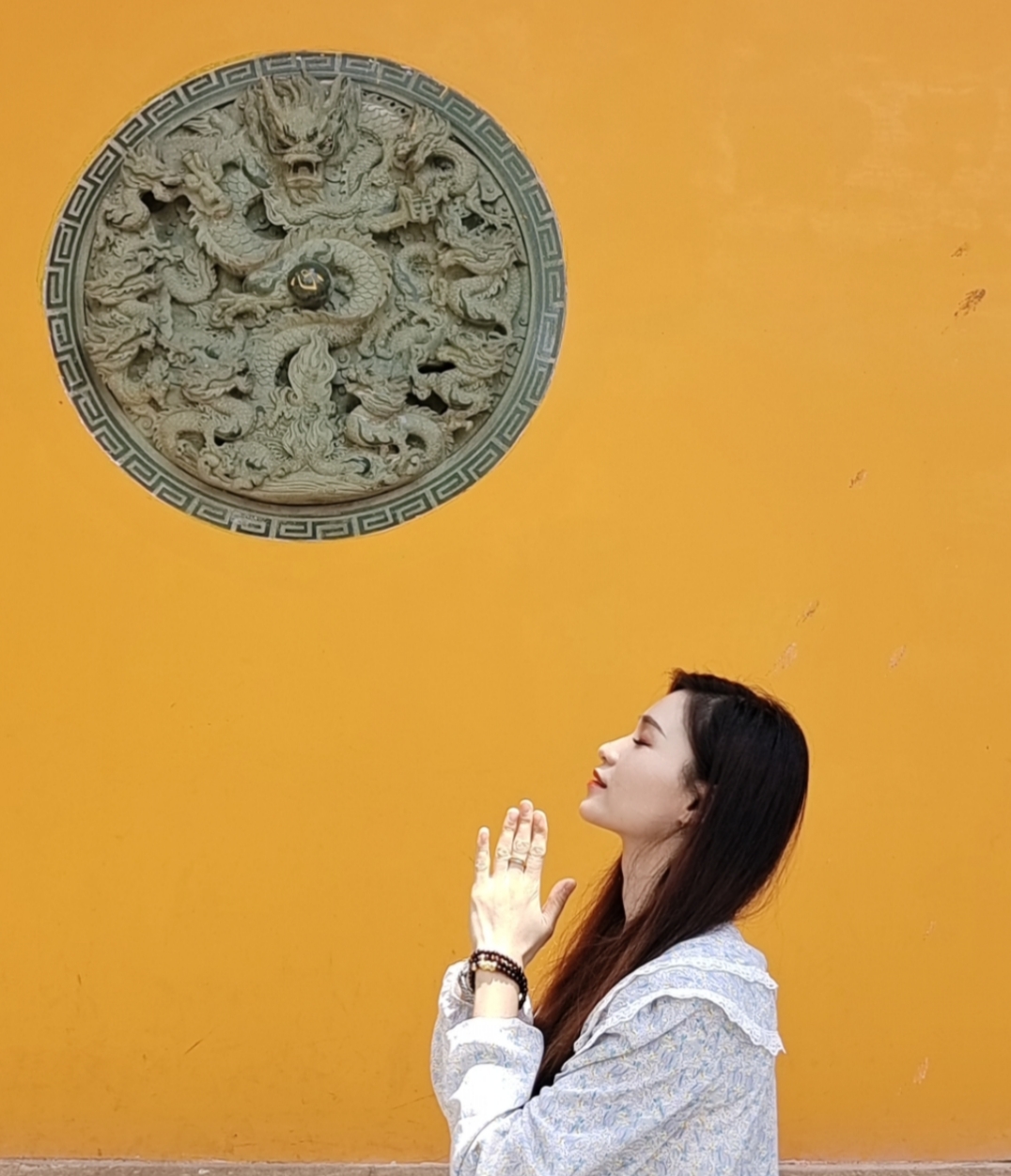 女子在古建筑前虔诚祈祷的画面
