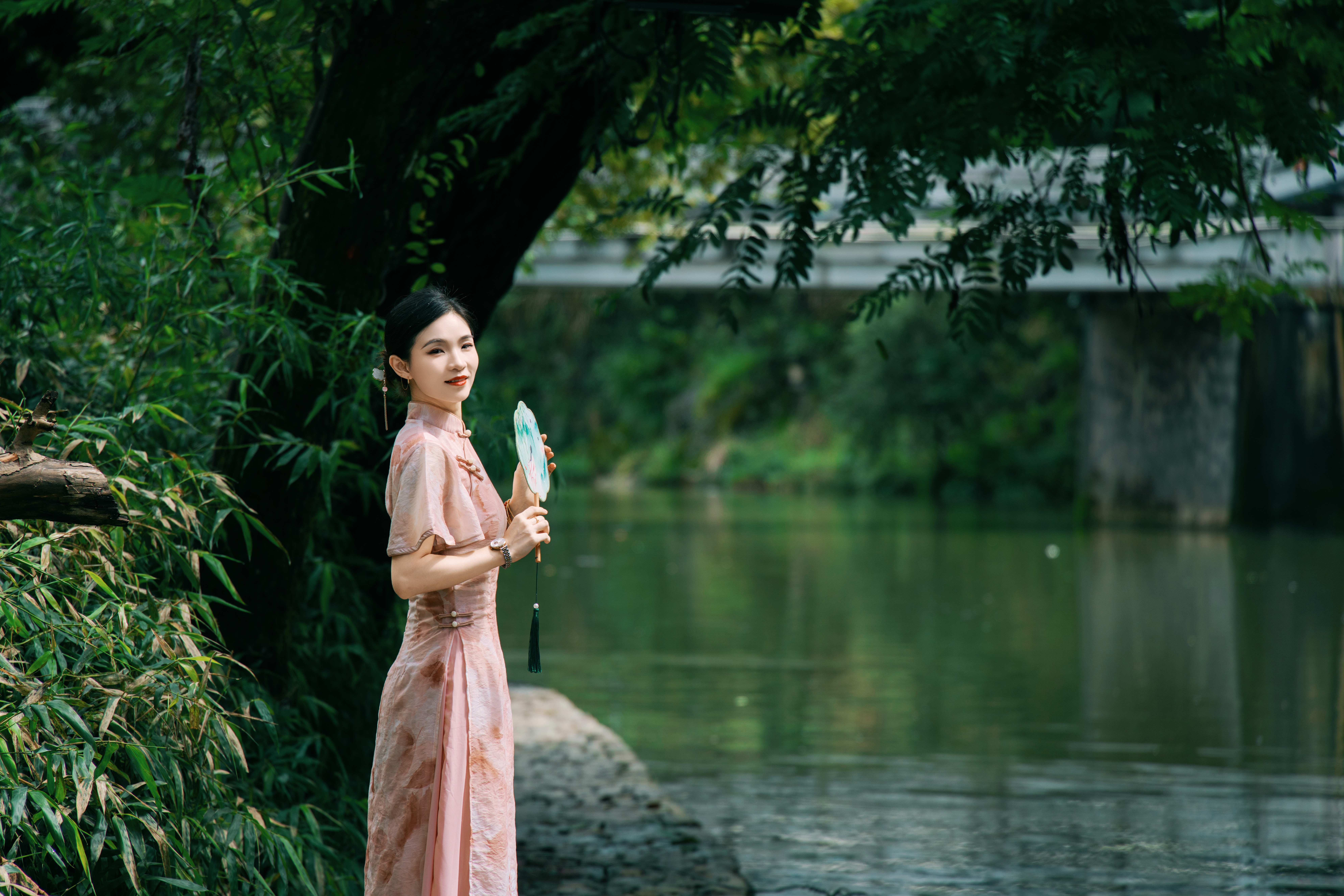 粉色旗袍佳人手持团扇立湖畔优雅