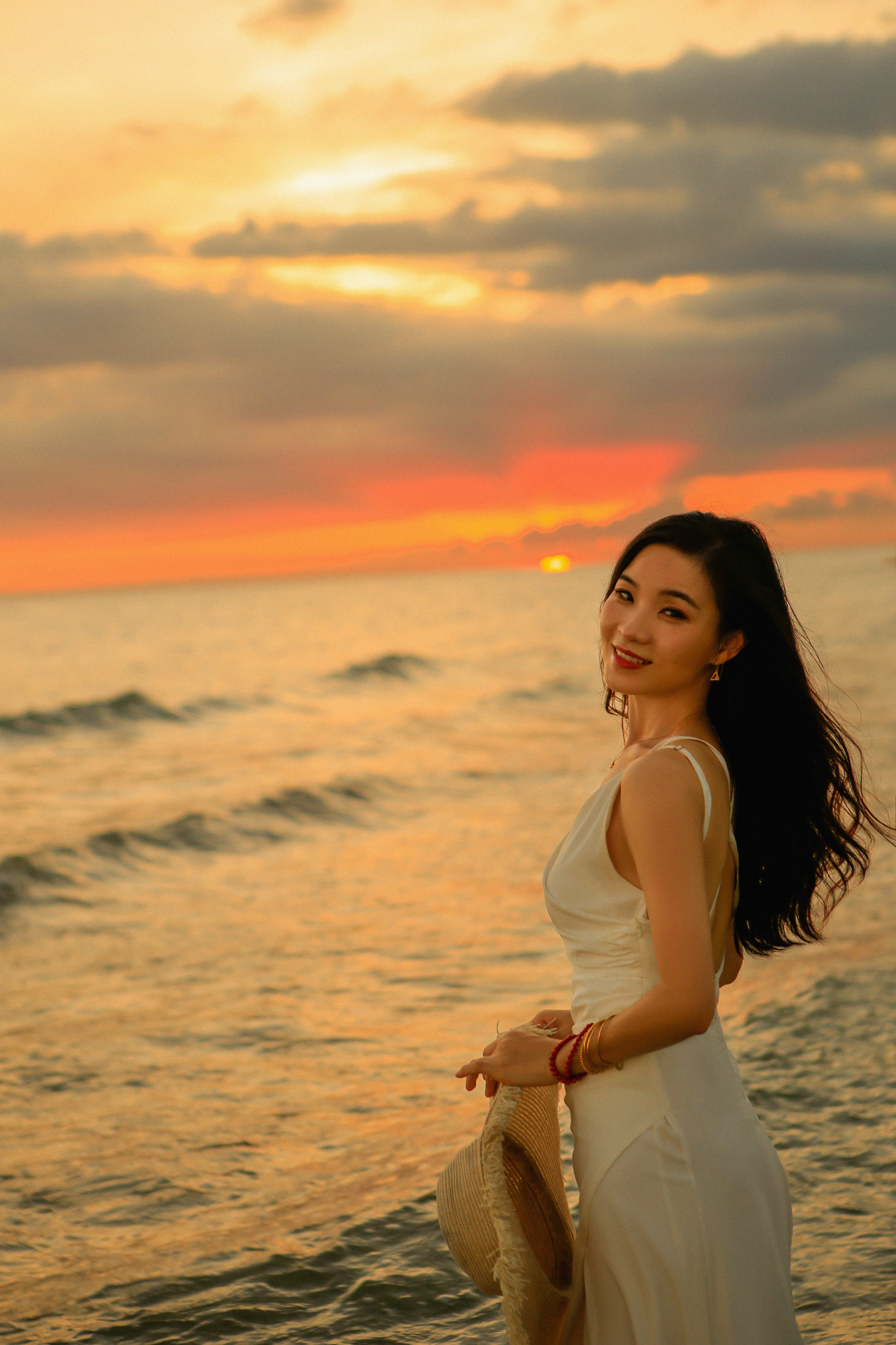 身穿白色连衣裙的女子在海边日落