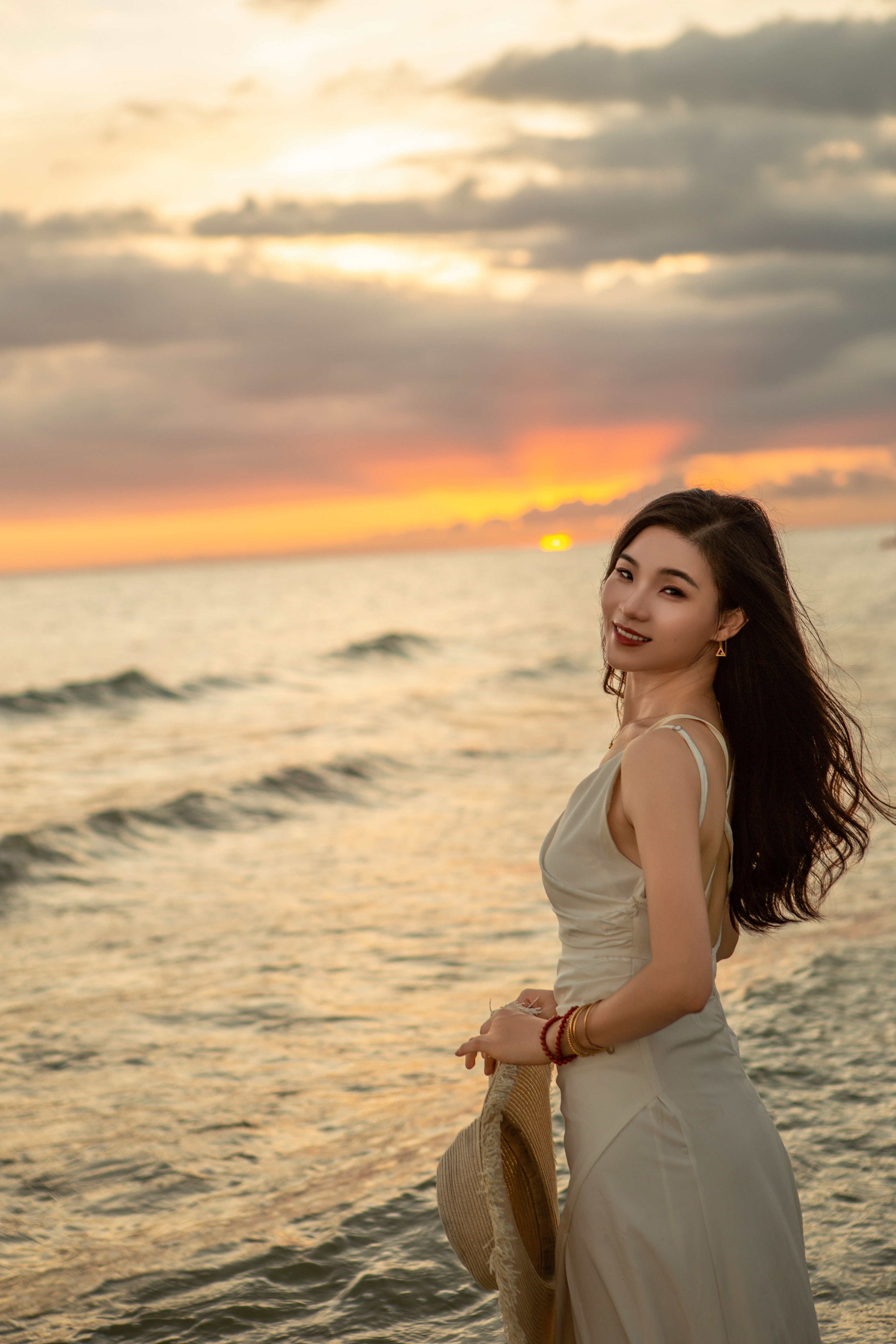 身穿白色长裙的女子在海边赏日落