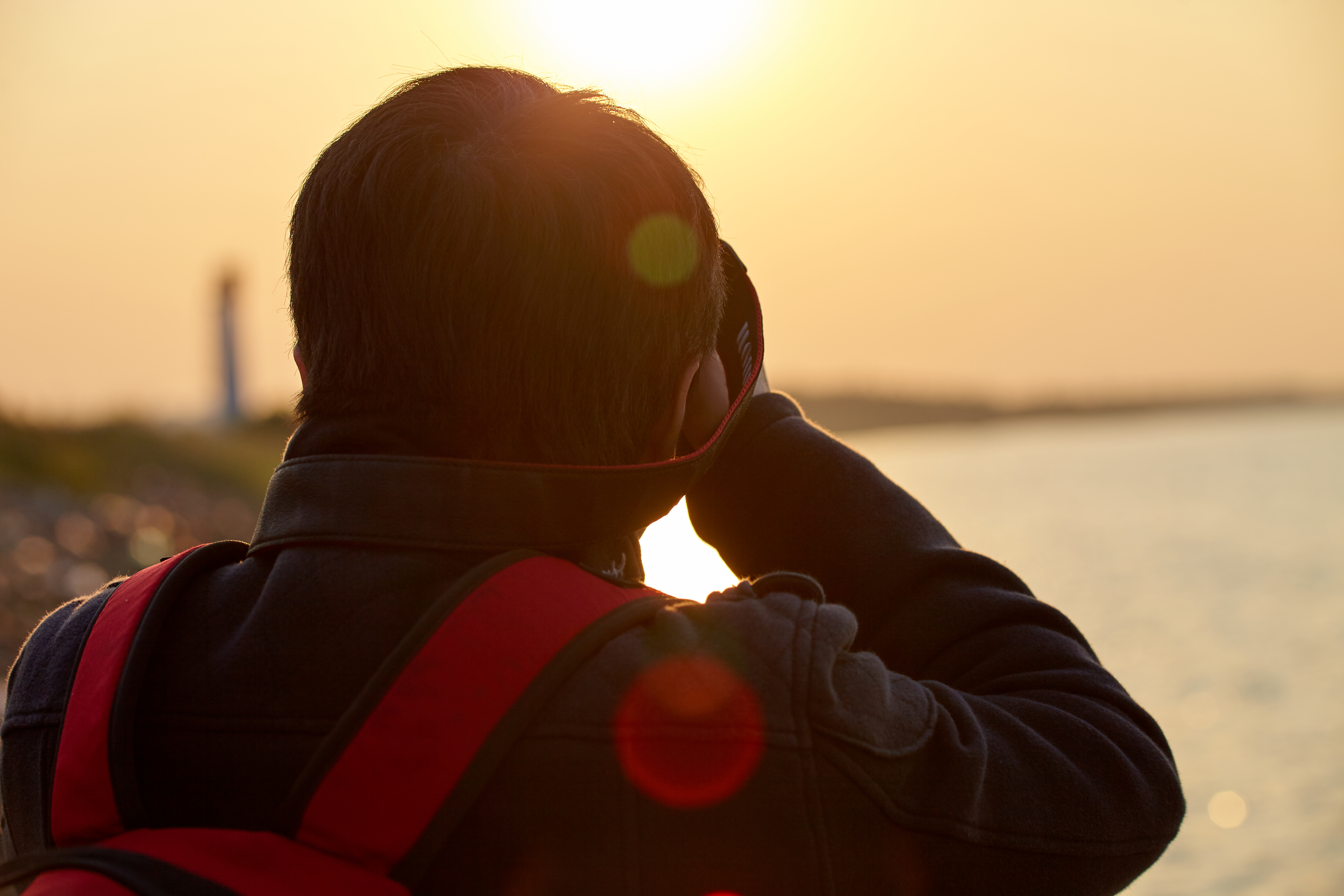 男子海边拍摄夕阳美景