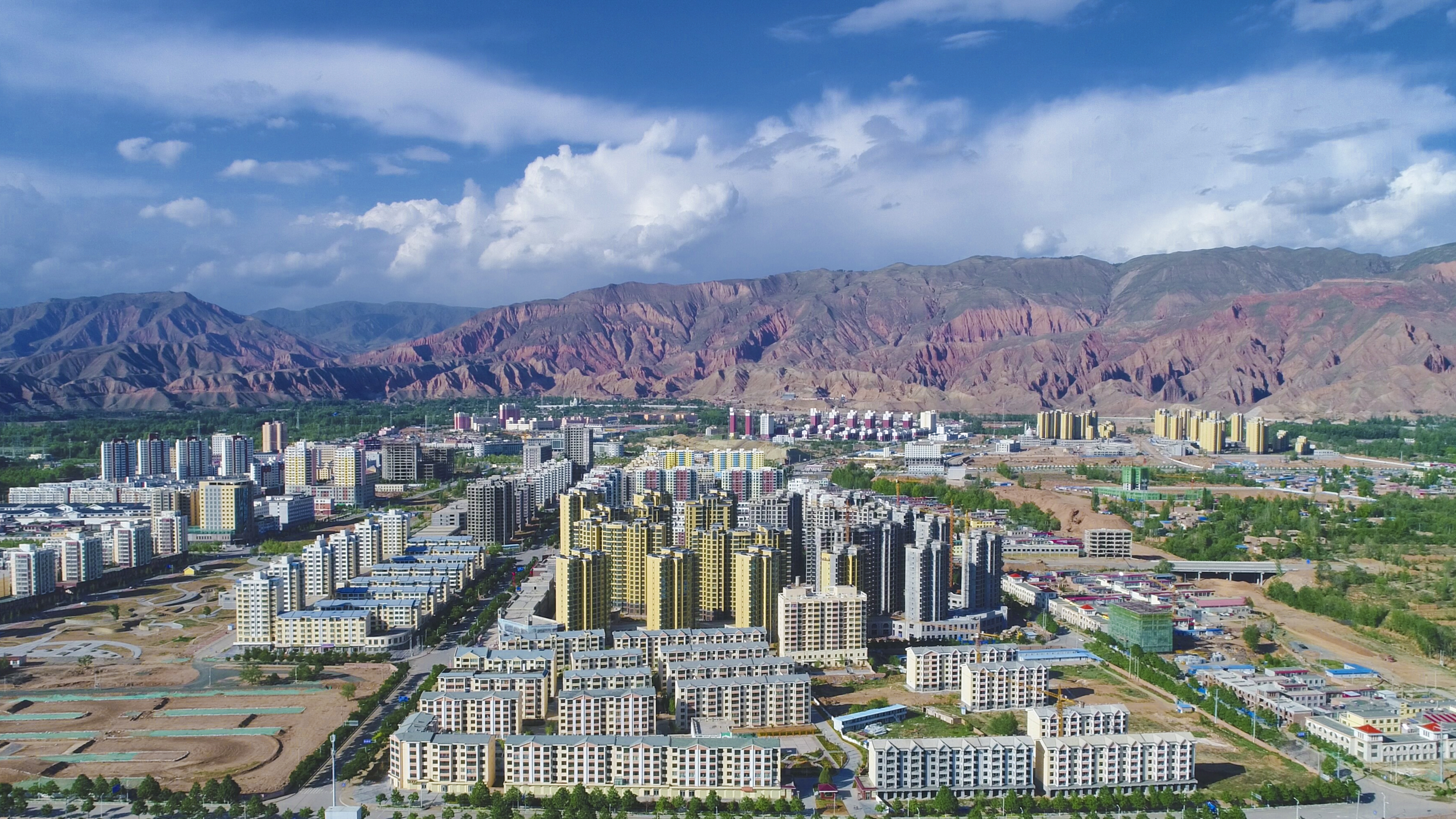 城市风貌尽显，壮阔山脉下的现代建筑群